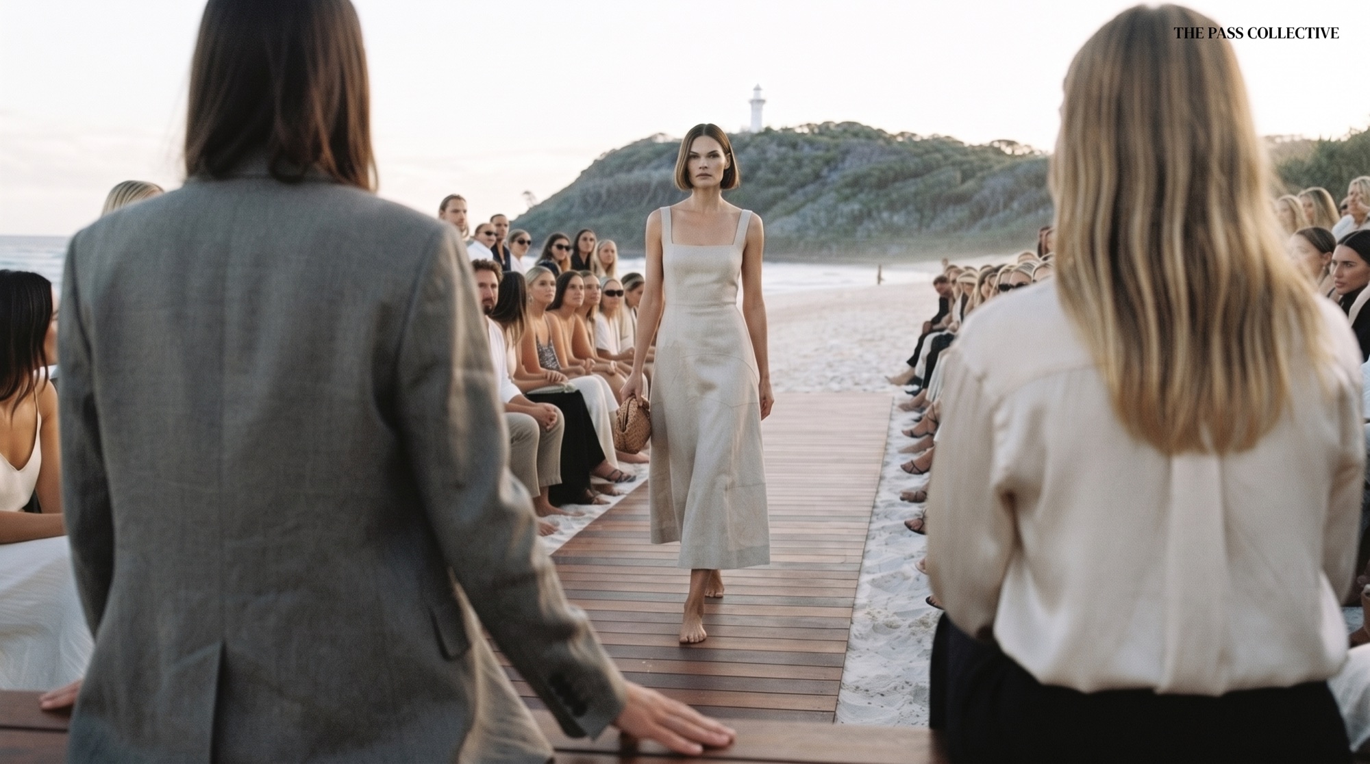 Concept visualisation of a model in a cream dress walking down a beach runway beneath the Cape Byron Lighthouse